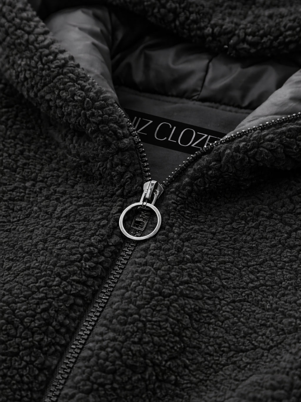 Close-up of a black fleece jacket with a zipper, featuring the brand 'HIZ Clozet'.